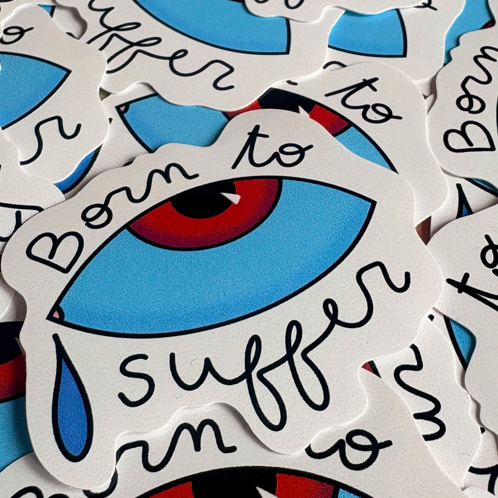 Gros plan de stickers « Born to suffer », avec un œil bleu, un iris rouge et une larme.