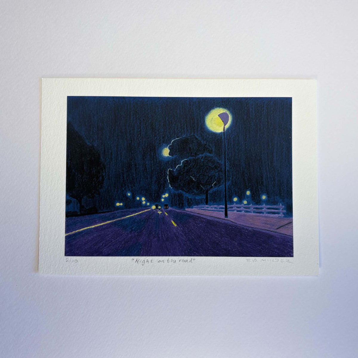 Tirage « Night on the road » avec marge blanche, représentant une route de nuit éclairée par des lampadaires.
